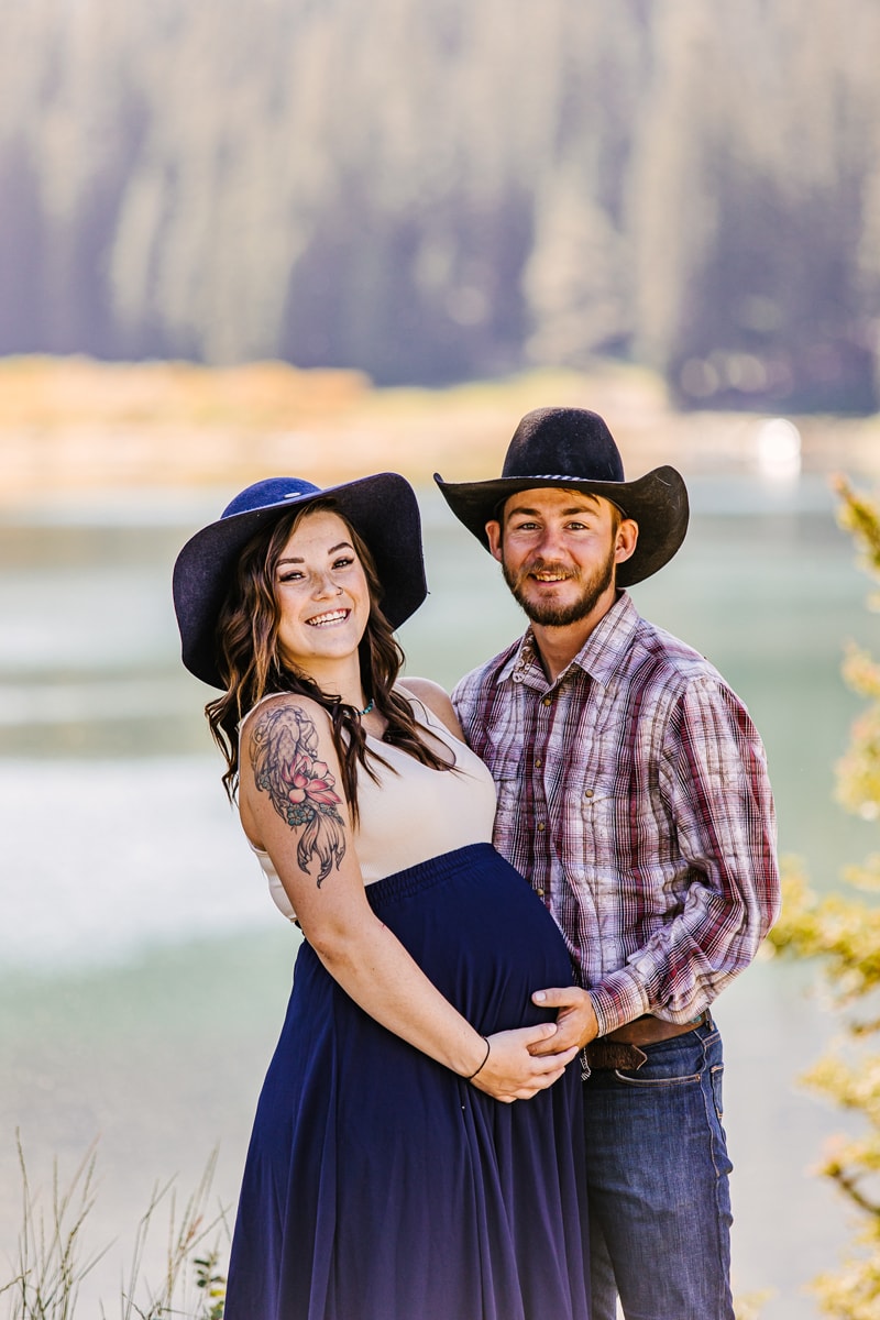 Maternity Photographer, a young couple stand near lake, she is pregnant