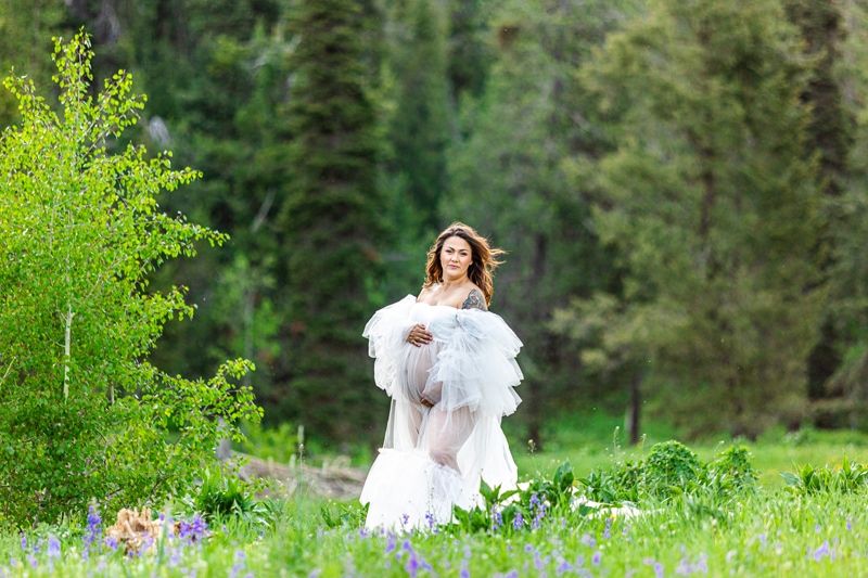 Maternity Photographer, an expectant mother stands in grass and wildflowers