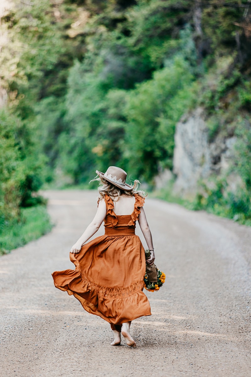 Senior Photographer, A woman walks down country roads with sunflowers in her hand