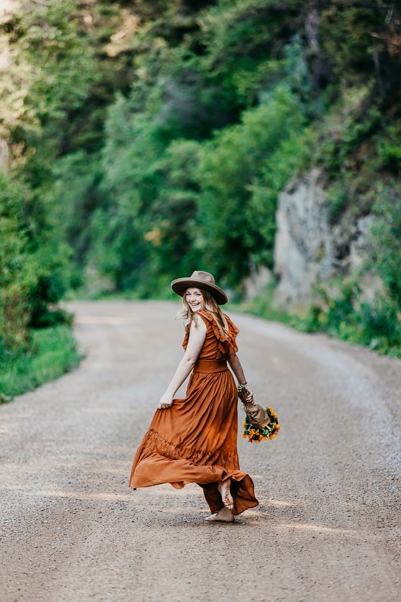 Senior Photographer,  a woman walks down a dirt road smiling