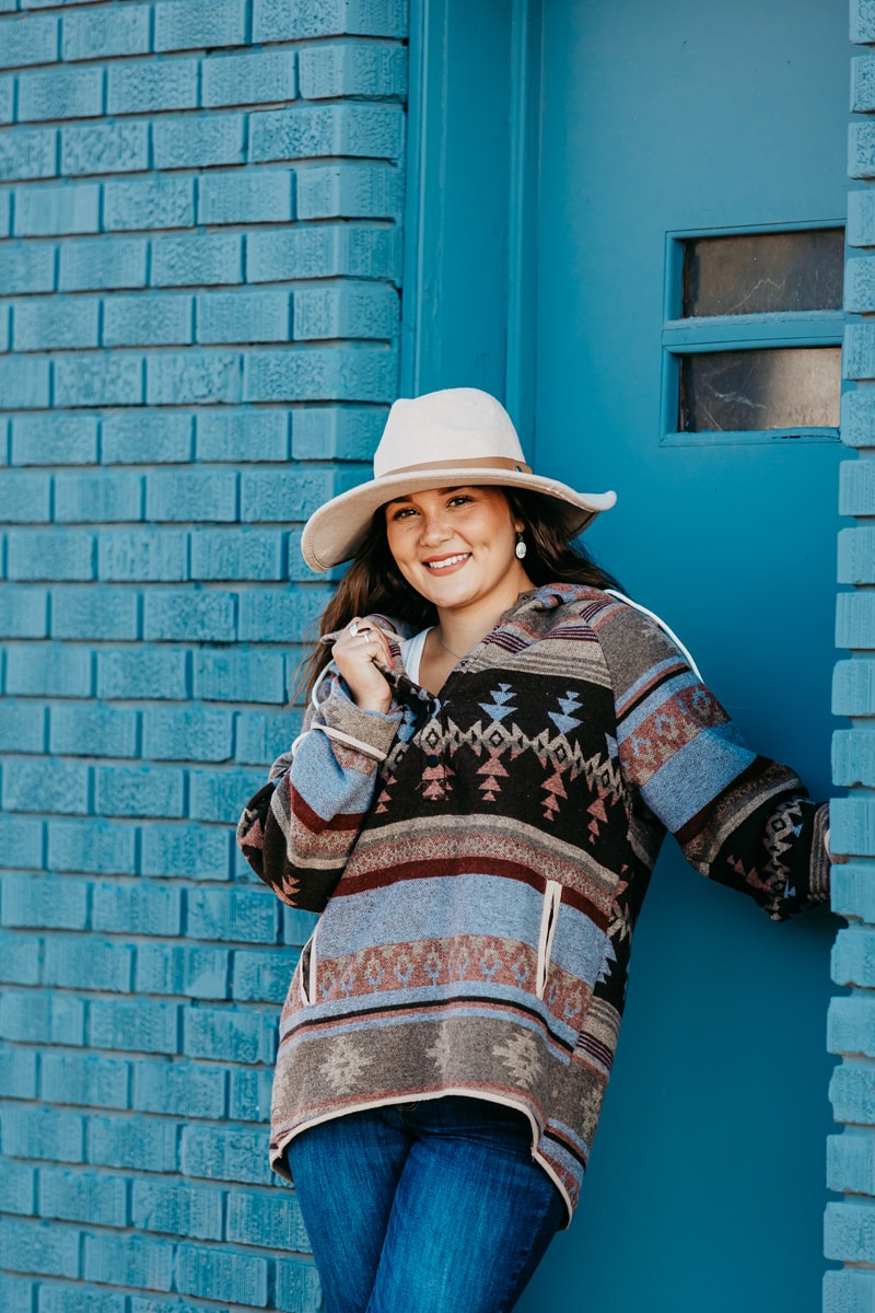 Senior Photographer,  a high school girl reclines on a blue brick wall and smiles