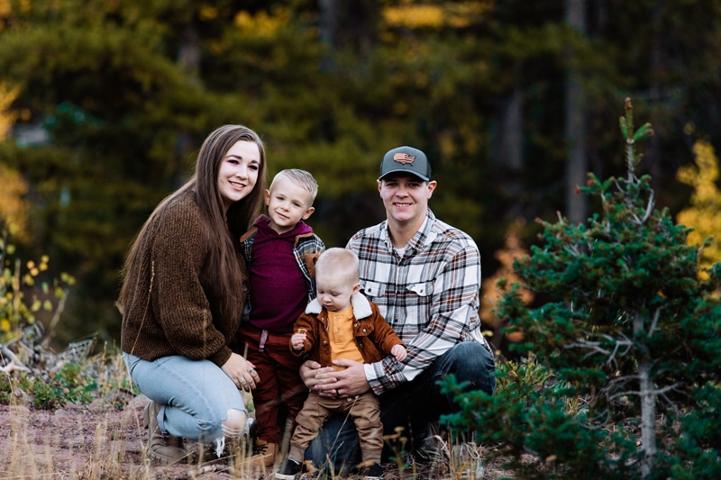 Family Photographer, a husband and wife kneel with their two boys in the woods