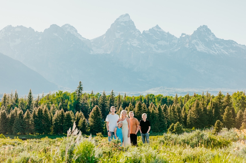 Family Photographer, a mother stands with her three children before the forest and mountains