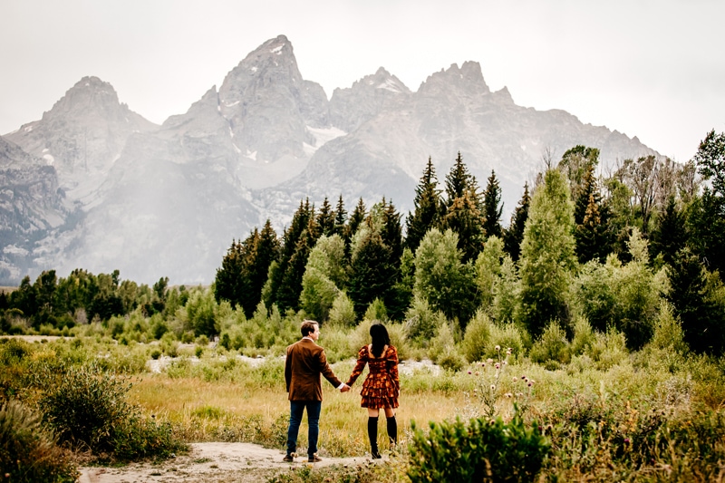 Couples photographer, a man and woman hold hands in mountain meadows