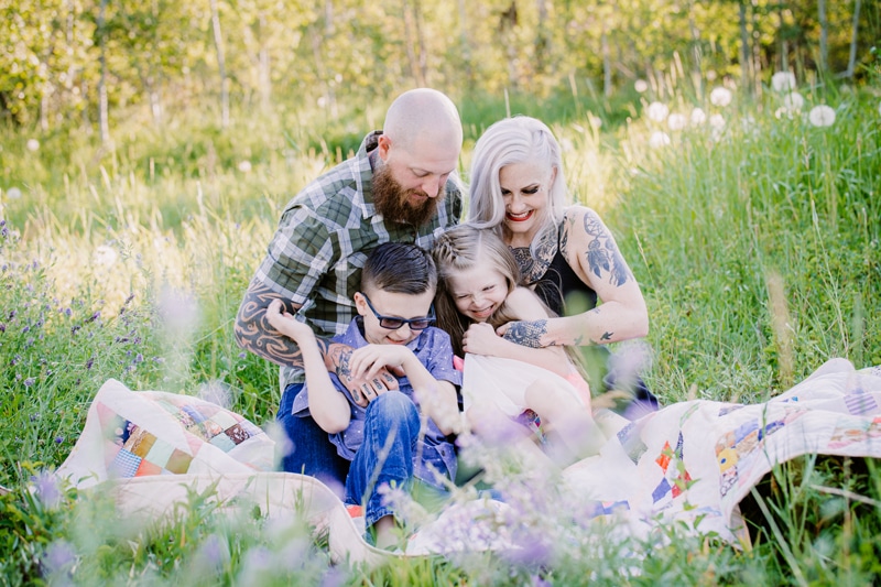 Family Photographer, a young man and woman snuggle their two children on a  blanket in the grass