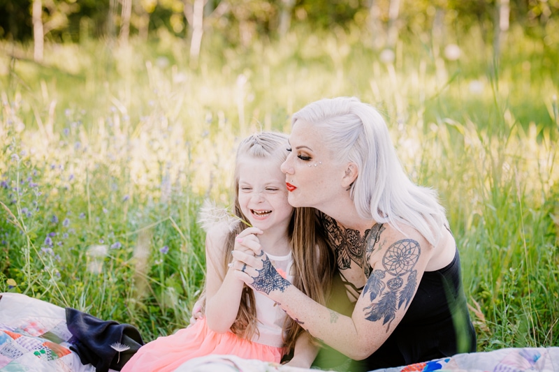Family Photographer, a mother blows a dandelion as her daughter giggles beside her