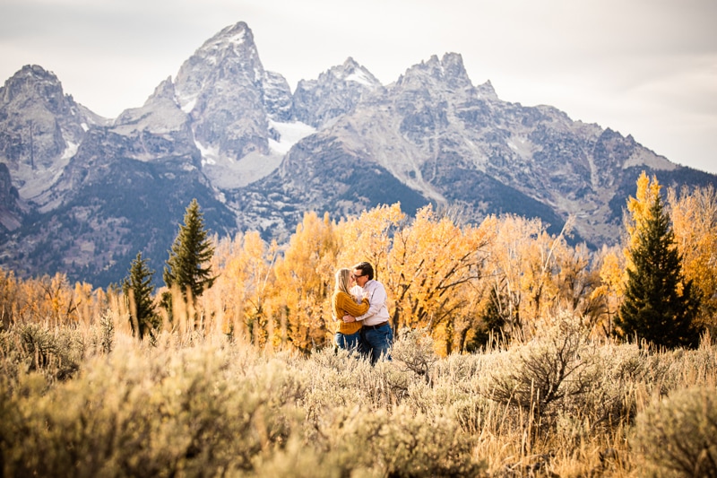 couples Photographer, a man and woman kiss as they embrace before the mountains