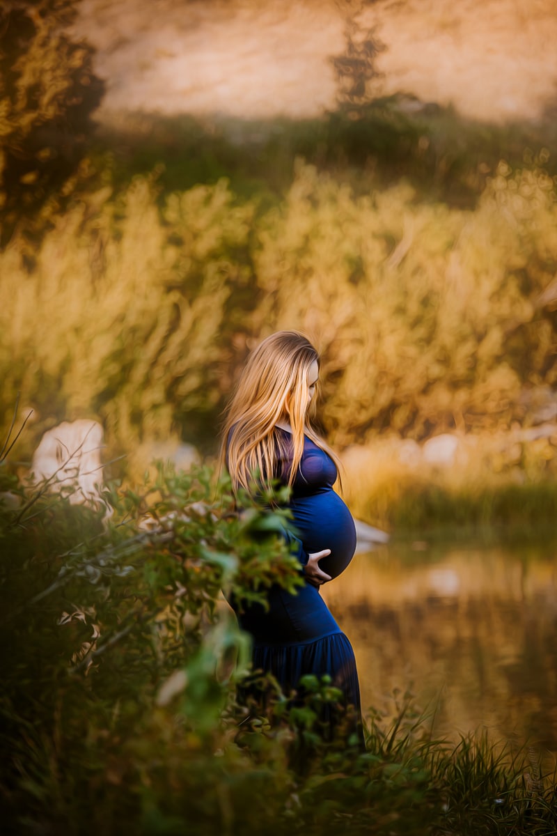 Maternity Photographer, a young mother-to-be stands near a lake