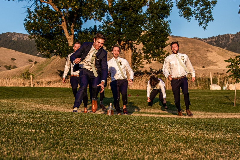 Wedding Photography, groomsman frantically run, laugh, and fall as they try to get a liquor bottle on the golf course