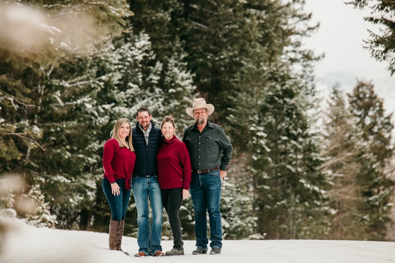 Family Photographer, a man, woman and his parents stand in the snow covered forest