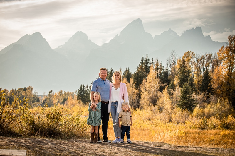 Family Photographer, a mother and father stand with their two young children in the mountains