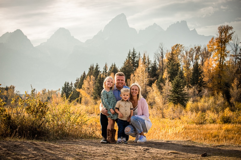 Family Photographer, a man and woman stand with their young kids in the mountains in the fall