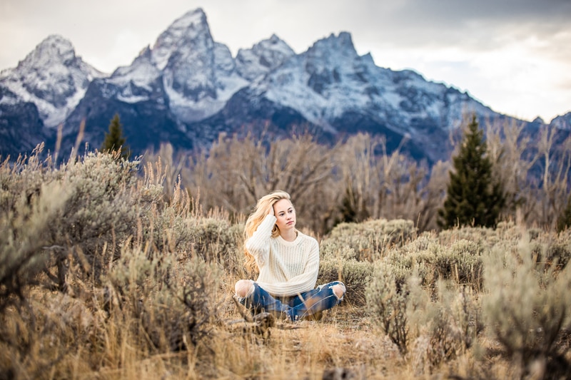 Senior Photographer, a young woman sits in the chaparral near the mountains