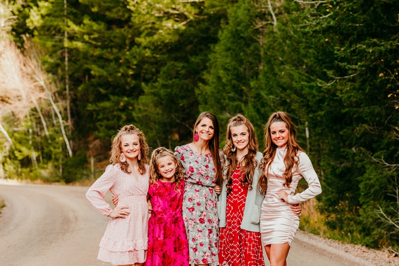 Family Photographer, a mother stands with her four daughters on a country road, they're all dressed up