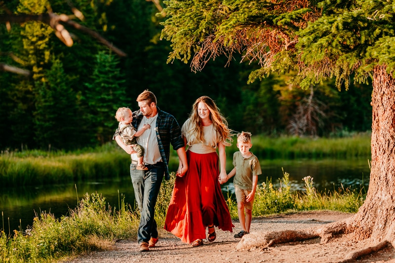 Family Photographer, mom and dad walk with their boys in a path through the woods