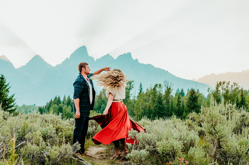Family Photographer, a man and woman dance near the woods and mountains outside