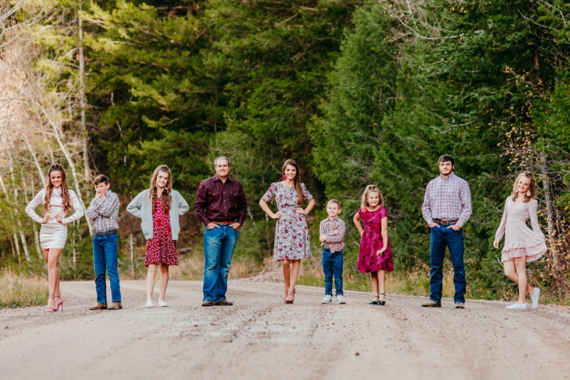 Family Photographer, a man and woman stand on a country road with their seven kids lined up beside them