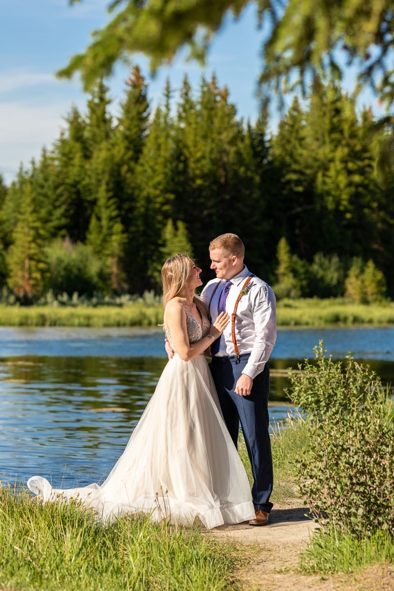 Wedding Photography, a bride and groom stand before a quiet river on a sunny day
