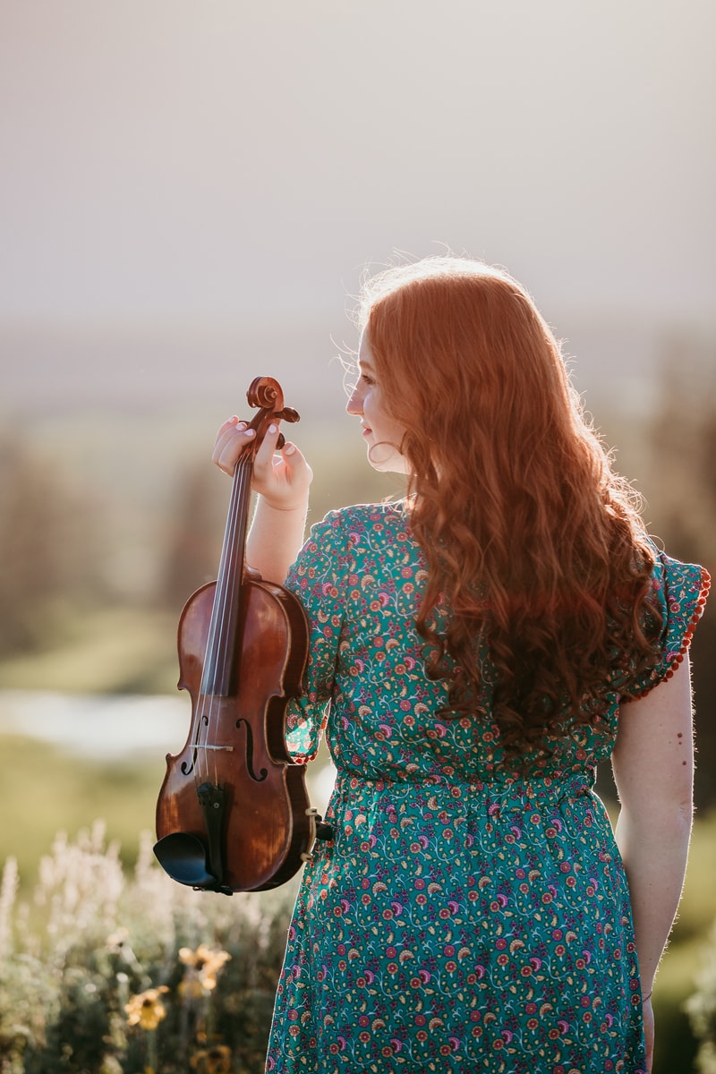 Senior Photographer, a woman in a dress holds a violin