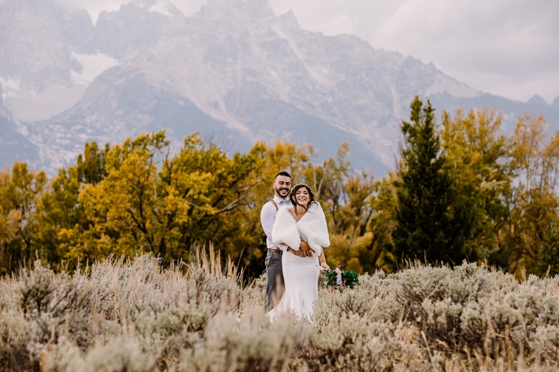 Wedding Photography, a groom holds his bride near mountains and forest